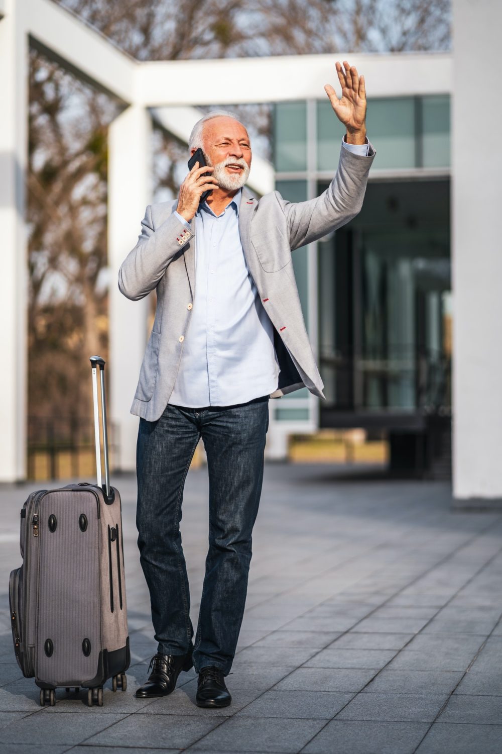 senior man calling a taxi with luggage bradford
